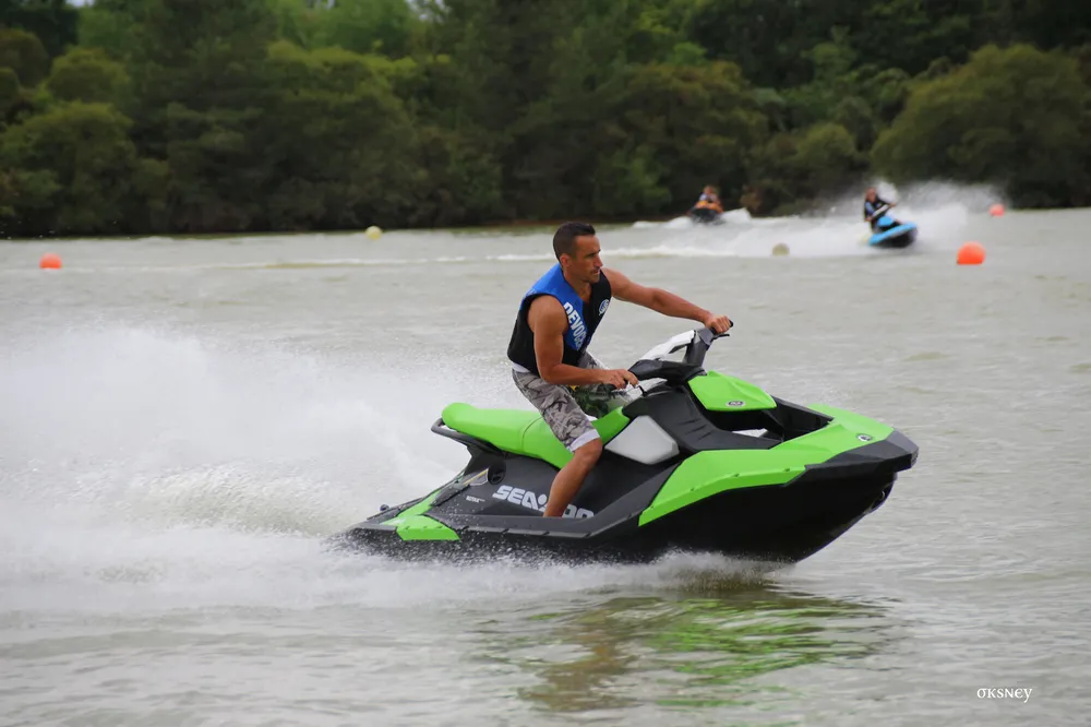 Homme pilotant un jet ski vert et noir sur un plan d'eau, activité nautique parc aventure